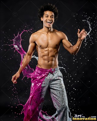 A shirtless smiling man splashed with pink liquid and water splashes