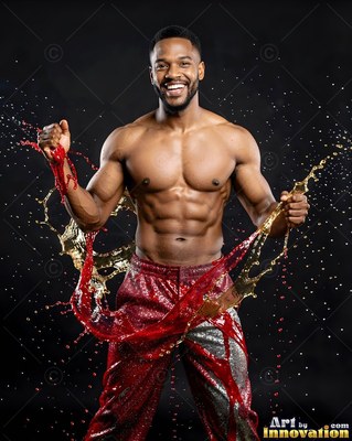 Smiling broadly, a muscular man poses as red and gold liquids splash around him