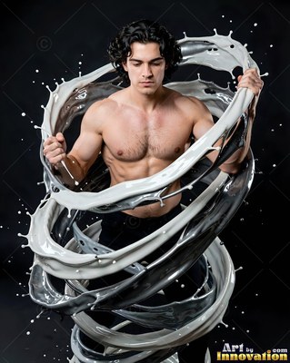 Standing in a dark studio, a shirtless man is ringed by swirling white liquid splashes