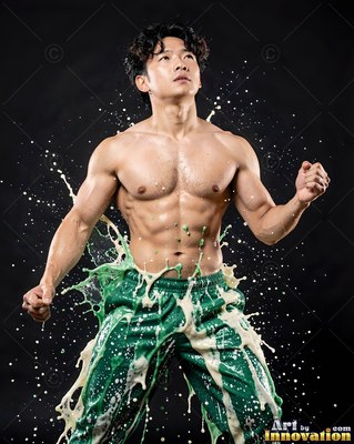 Green patterned pants in a dark studio worn by a muscular man as white liquid splashes