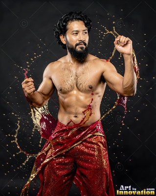 A shirtless bearded man poses in red pants as gold liquid splashes around him