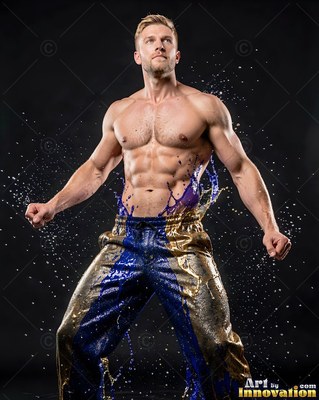 A muscular shirtless man poses as blue liquid and water droplets splash across his gold pants
