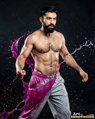 In a dark studio, a shirtless man braces as pink liquid and water splash past him