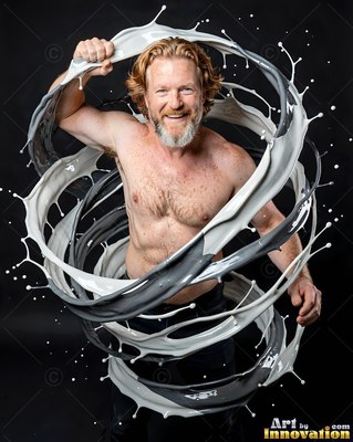 Bearded shirtless man in a dark studio surrounded by swirling loops of gray paint