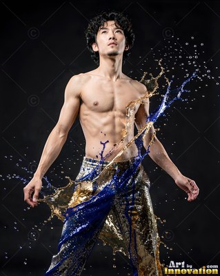 Standing in a dark studio, a shirtless man is splashed with blue and gold liquid