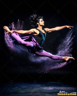 In a dark studio, a man leaps through a cloud of purple powder