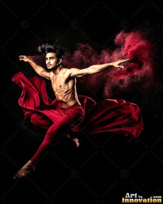 Leaping in midair, a shirtless man dances with red fabric and red powder on black