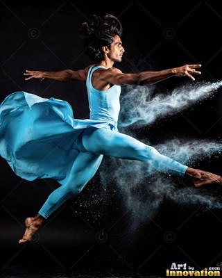 Man leaps in a light blue suit with powder in the air