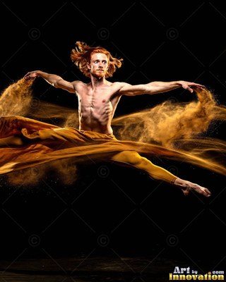 Red hair flying back, a shirtless man leaps through gold powder in a dark room