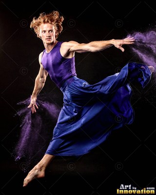 A man leaps in purple and blue clothes, throwing clouds of purple powder