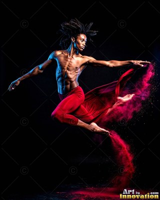 A shirtless man leaps through the dark air in red pants, trailing bright magenta powder behind his feet