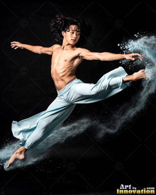 A shirtless man leaps through dark space, trailing pale blue powder from his extended foot