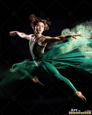 Leaping midair in a dark studio, a man dances with green powder and fabric