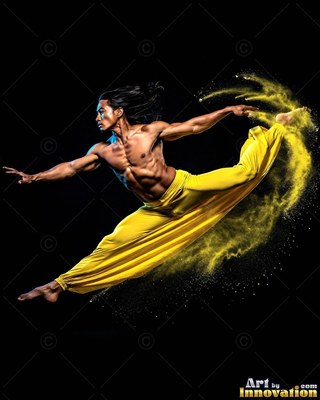 A shirtless man leaps in yellow pants while kicking up bright yellow powder