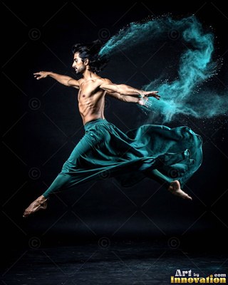 Leaping midair in a dark studio, a shirtless man trails turquoise powder