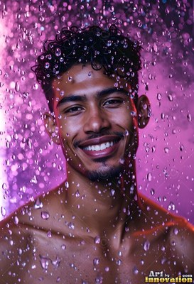 Under purple light, a smiling man without a shirt stands in water coming down droplets