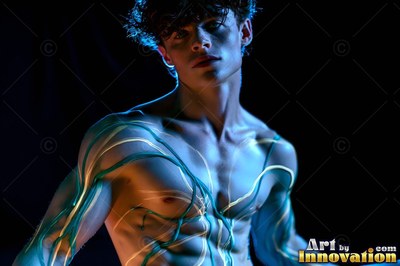 A shirtless man turns slightly as green and yellow lines of light cross his torso