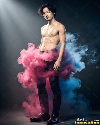A shirtless man stands wrapped in pink and blue smoke under a cool spotlight