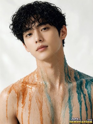 A shirtless young man gazes forward as orange and blue liquid streams down his skin