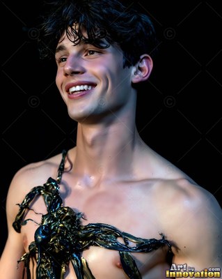 A smiling young man turns his head with thick black paint splashed on his chest