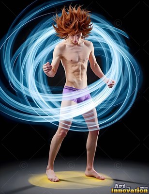 In a dark space, a man in purple shorts stands encircled by bright blue trails of light