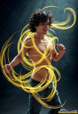 Curly dark hair frames a smiling man without a shirt circled by loops of bright yellow light in a dark studio