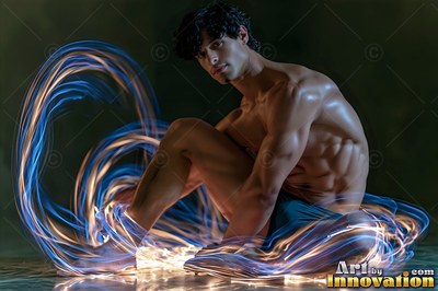 In a dark room, a bare-chested man sits inside swirls of blue and gold light
