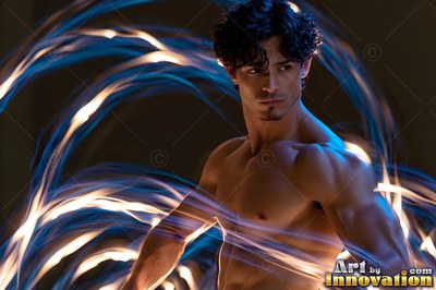 Posing shirtless, a muscular man stands circled by curving blue and white ribbons of light