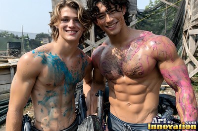 At an outdoor paintball field, two bare-chested men smile with blue and pink paint on their bodies