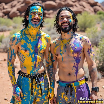 Standing side by side in the desert, two smiling men covered in yellow and bright blue paint