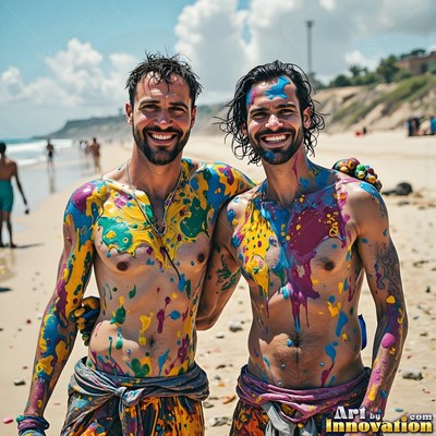 Two grinning bare-chested men stand on a sunny beach covered in colorful paint splashes