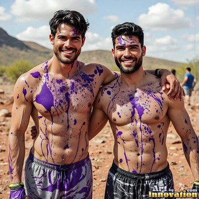 Splattered purple paint covers two shirtless men smiling together in the sunny desert