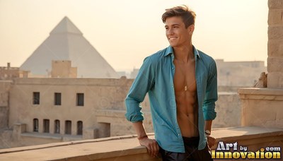A grinning man wearing an unbuttoned blue shirt leans on a stone balcony by a pyramid
