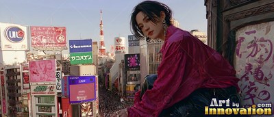 A young man in a magenta shirt sits on a Tokyo rooftop