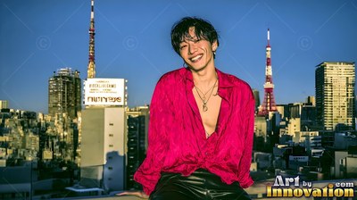 Smiling Japanese man in an open red shirt on a Tokyo rooftop