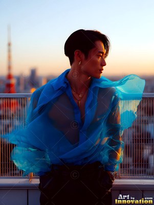 On a rooftop at sunset, a young man wears a sheer blue shirt that catches the wind
