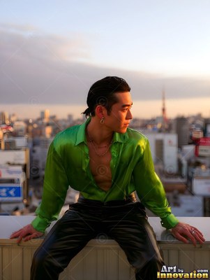 A man in an open green silk shirt rests on a tokyo rooftop at sunset