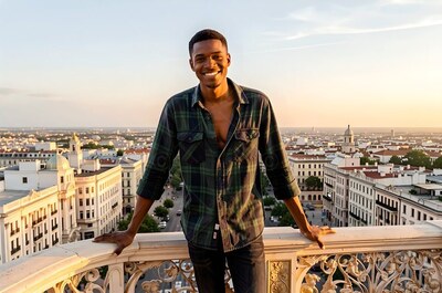 Smiling man in an unbuttoned plaid shirt on a balcony above the city