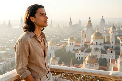 A man in an unbuttoned tan shirt looks out over golden domes from a rooftop balcony