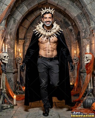 A skull crown tops a smiling bare-chested man walking through a stone crypt with skulls