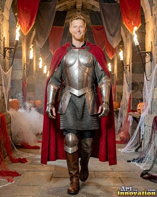A cheerful man in shiny knight armor and a red cape walks down a stone hallway