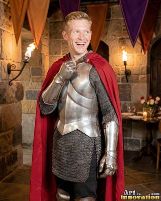Smiling in stone halls, a blond man wears steel armor with a red cape