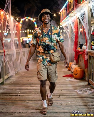 Man in a tourist costume walks past cobwebs and pumpkins