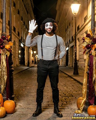 On a cobblestone street at night, a smiling man dressed as a mime waves hello