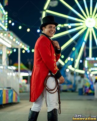 Smiling man in a red ringmaster coat holding a whip at a carnival