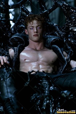 A man without a shirt with red hair sits on a black throne
