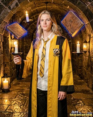 Standing straight in a stone hallway, a blond man wears yellow and black robes