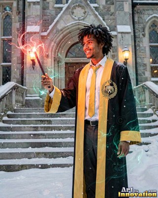 Holding up a wand, a smiling man in a black and yellow robe stands in the snow