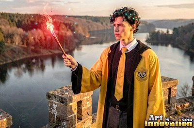 In a yellow robe, a man raises a flaming wand above a quiet river valley