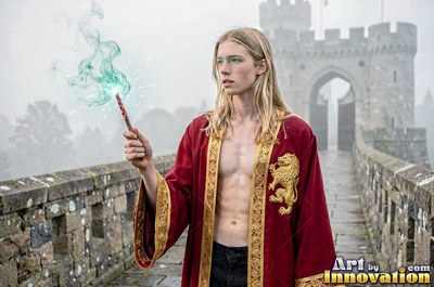A young blond man in an unzipped red robe holds a wand on a castle bridge
